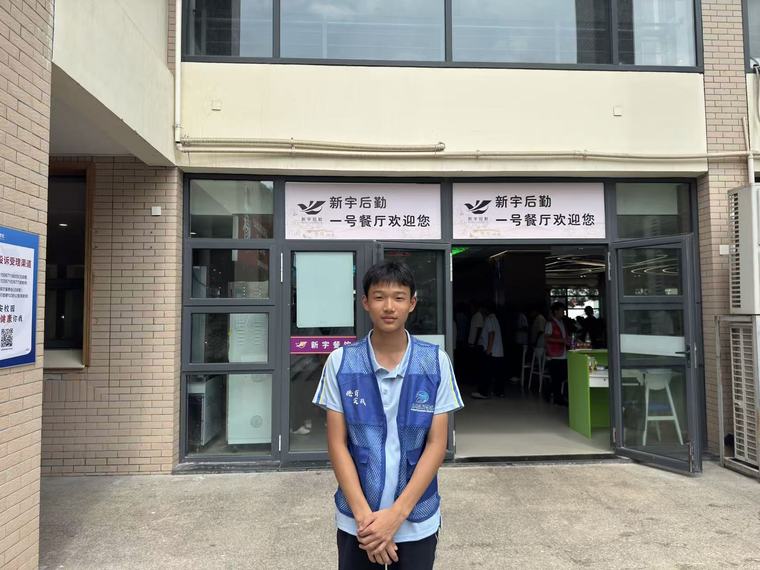 一位同学双手交叠站在一号餐厅门口