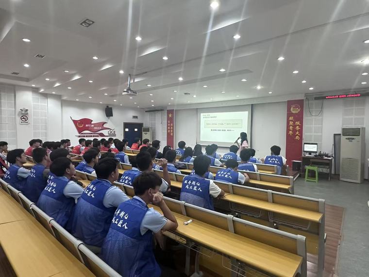 报告厅里，穿蓝色马甲的同学们整齐就座听讲