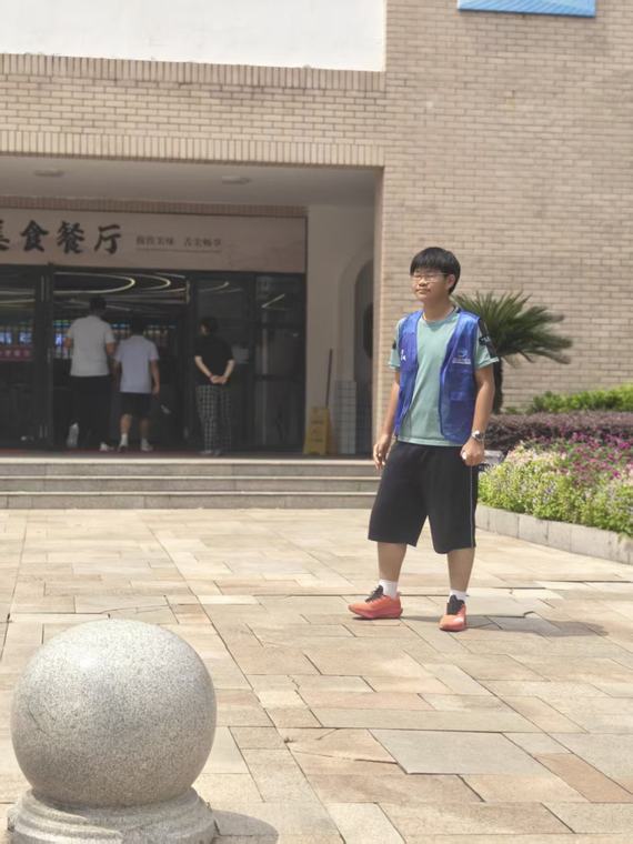 一位同学穿着马甲从餐厅门前的广场走过