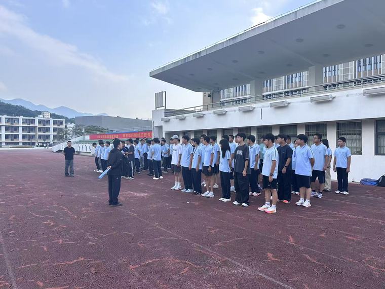 FJ2601 全班同学在操场跑道上列队，背景是看台和远处的山