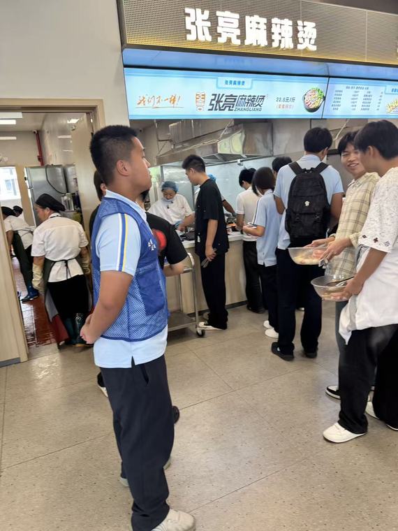 同学们在食堂麻辣烫窗口前排队打饭